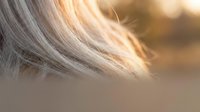 Close-up of silky blonde hair strands glowing in warm golden light, showcasing smooth texture and shine for beauty and haircare concepts.