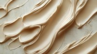Creamy beige foundation makeup smears and swatches on textured surface showing smooth blendable coverage for cosmetic beauty applications.