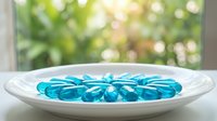 Blue glass marbles arranged in white ceramic plate on windowsill with natural sunlight and green foliage background creating peaceful home decor scene.