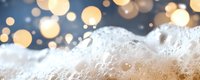 Macro shot of beer foam with golden bokeh lights in background creating festive atmosphere. Fresh bubbles and froth close-up for beverage and celebration designs.