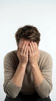 Stressed young Caucasian man covering face with hands showing frustration, anxiety and mental health struggles isolated on white background.