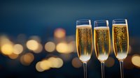Three elegant champagne flutes filled with sparkling wine against blurred city lights background, golden bubbles rising in glasses create festive luxury atmosphere.