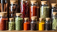 Colorful spice jars with cork lids arranged on wooden shelf containing various herbs, seasonings and cooking ingredients for culinary preparation.