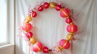 Festive paper lantern wreath with pink and gold ornaments and cherry blossom branches for spring celebration decor and party decoration.