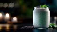 Refreshing mint smoothie in glass jar with crushed chocolate cookies and fresh mint leaves on dark background with bokeh lights, selective focus.
