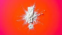 White powder explosion burst on vibrant pink orange gradient background for cosmetic beauty product advertising and creative design projects.