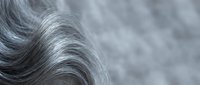 Close-up of silver gray wavy hair texture with soft bokeh background, showcasing natural aging beauty and elegant hair care concept.