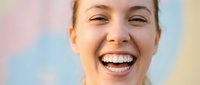 Young Caucasian woman laughing joyfully with bright white teeth against colorful pastel background for wellness and happiness campaigns.