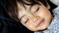 Peaceful sleeping Asian child with gentle smile resting on dark pillow, close-up portrait showing innocence and tranquility. For parenting and lifestyle content.