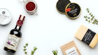 Luxury gourmet food products with caviar, wine, cheese and herbs arranged on white background for culinary branding and premium dining concepts.