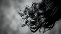 Flowing dark hair strands in motion captured in artistic black and white photography for beauty and haircare concepts.