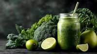 Fresh green smoothie in mason jar with kale, broccoli and lime slices on dark background. Healthy detox drink concept for wellness and nutrition lifestyle.