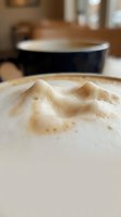 Close-up of creamy latte with decorative foam art in ceramic cup, suitable for coffee shop menus, cafe marketing, and beverage advertising.
