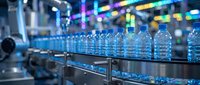 Rows of clear plastic water bottles on industrial conveyor belt in beverage manufacturing facility with blurred production equipment background.