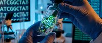 Scientist in blue gloves holds glass vial with glowing green microorganisms in lab with DNA sequence data on screens.