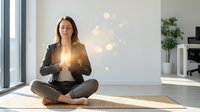 Young Caucasian businesswoman in suit meditating in lotus position on yoga mat in modern office space with warm lighting for mindfulness and wellness.