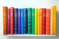 Row of colorful vintage hardcover books arranged in rainbow spectrum order standing on white wooden shelf, spines showing classic literature collection.