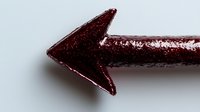 Red glittery arrow pointing left on white background, metallic textured directional symbol for graphic design, presentations and navigation elements.