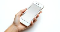Female hand holding white smartphone with blank screen on white background, mockup for app or web design presentation. Clean minimal composition.