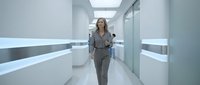 Woman in business attire walking through modern corridor with minimalist design, suitable for corporate, professional, and workplace concepts.