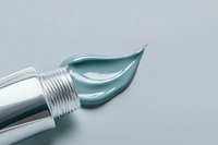Mint green cosmetic cream squeezed from metallic tube on pastel background, showcasing smooth texture for skincare product advertising.