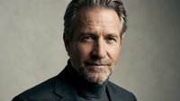 Middle-aged man with gray hair and facial hair wearing dark turtleneck against neutral background. Professional headshot suitable for corporate, business, and editorial use.