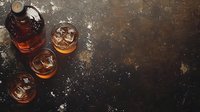 Whiskey bottle and glasses with ice cubes on dark rustic background. Overhead view of premium alcohol drink with dramatic lighting and copy space.