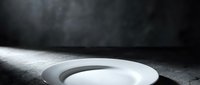 Empty white plate on dark textured surface with dramatic lighting, suitable for food photography, restaurant menus, culinary blogs, and dining concepts.