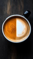 Fresh cappuccino in white ceramic cup with distinctive foam art and rich crema on dark wooden background, viewed from above. Perfect for cafe menu and food blogs.