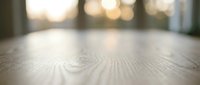 Close-up of wooden floor surface with natural grain texture and warm bokeh lighting in background, suitable for interior design and flooring projects.