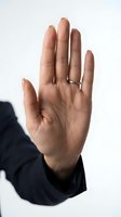 Open palm hand gesture showing stop sign with silver ring on finger against white background for communication and body language concepts.