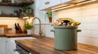 Modern kitchen interior with green ceramic pot on wooden countertop, white subway tile backsplash and warm lighting for home cooking and culinary design.