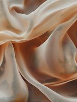 Flowing beige and brown silk fabric creates elegant waves and folds with soft shadows and highlights, showcasing luxurious textile movement and texture.
