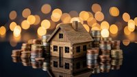 Wooden house model surrounded by stacks of coins with warm bokeh lights background representing real estate investment and property financing.