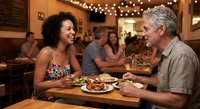 Happy interracial couple enjoying romantic dinner date at cozy restaurant with string lights and warm atmosphere creating intimate dining experience.