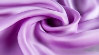 Luxurious purple silk fabric with elegant flowing curves and soft texture creating graceful waves for fashion and textile design projects.
