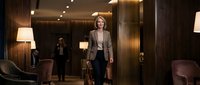 Professional businesswoman walking confidently through luxury hotel lobby with warm lighting and elegant interior design for corporate travel concepts.