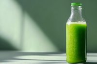Fresh green smoothie in glass bottle on light surface with natural shadow, healthy detox drink for wellness and nutrition lifestyle.