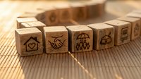 Wooden blocks with insurance icons arranged on bamboo mat representing coverage protection and financial security services.