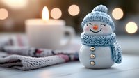 Cute white snowman figurine with blue knitted hat and scarf smiling on cozy winter table with warm candle lights and soft blankets creating festive holiday atmosphere.