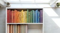 Colorful rainbow books arranged by color on white bookshelf creating organized library display for home decor and reading inspiration.