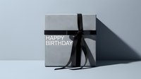 Elegant gray gift box with black ribbon bow and Happy Birthday text on light background, minimalist luxury present for celebration.