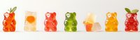 Colorful gummy bears with fruit garnish arranged in row on white background, sweet candy jellies in different flavors and colors showing transparency and texture.