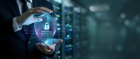 Businessman hands protecting digital firewall security shield with padlock icon over server room background for cybersecurity protection.
