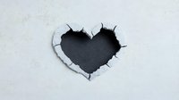 Heart shaped hole torn through white paper revealing dark background, dramatic ripped edges create depth and dimension for creative designs and valentines concepts.