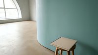 Minimalist interior with small wooden table against turquoise wall and natural light from arched window, suitable for home decor and design projects.