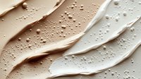 Creamy liquid foundation makeup swatches with water droplets showing different skin tone shades for beauty and cosmetics applications.