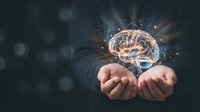 Human hands holding glowing brain with neural connections and light rays representing artificial intelligence, innovation and mental power concepts.