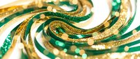 Elegant swirling ribbons in emerald green and gold with sparkling glitter effects creating luxurious festive decoration for holidays and celebrations.