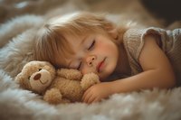 Peaceful sleeping Caucasian toddler girl with blonde hair cuddling soft teddy bear on cozy white fur blanket, gentle natural lighting creates dreamy atmosphere.